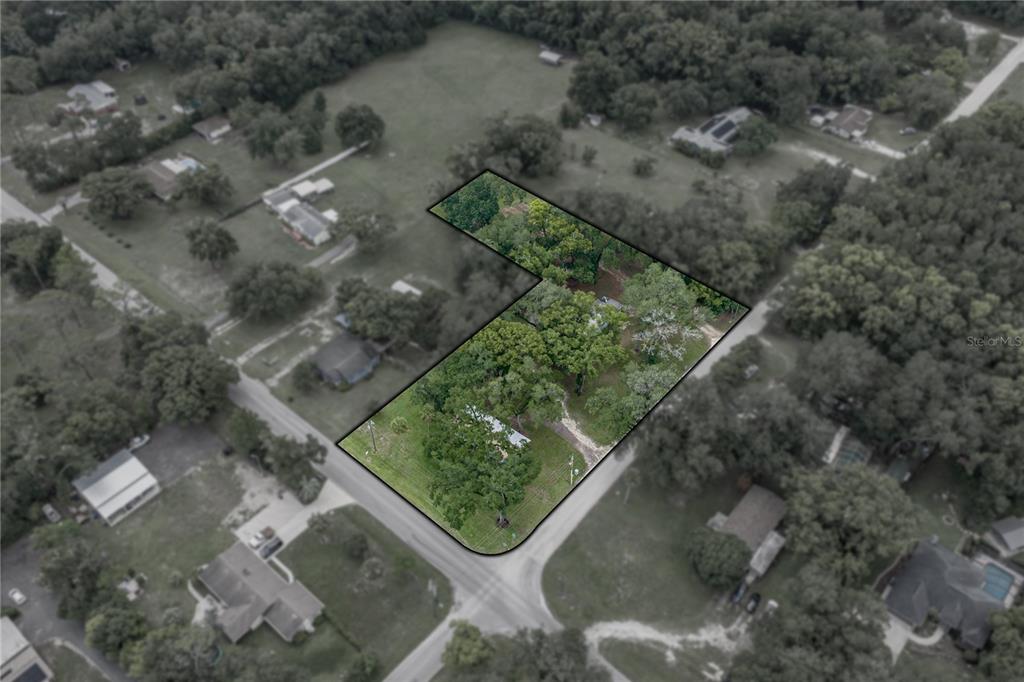 An aerial view shows an L-shaped residential lot with trees and a small structure — 7450 23RD STREET, ZEPHYRHILLS, FL