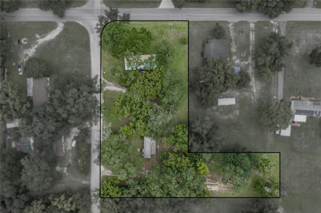 This is an aerial view of a property with two structures on a wooded lot — 7450 23RD STREET, ZEPHYRHILLS, FL