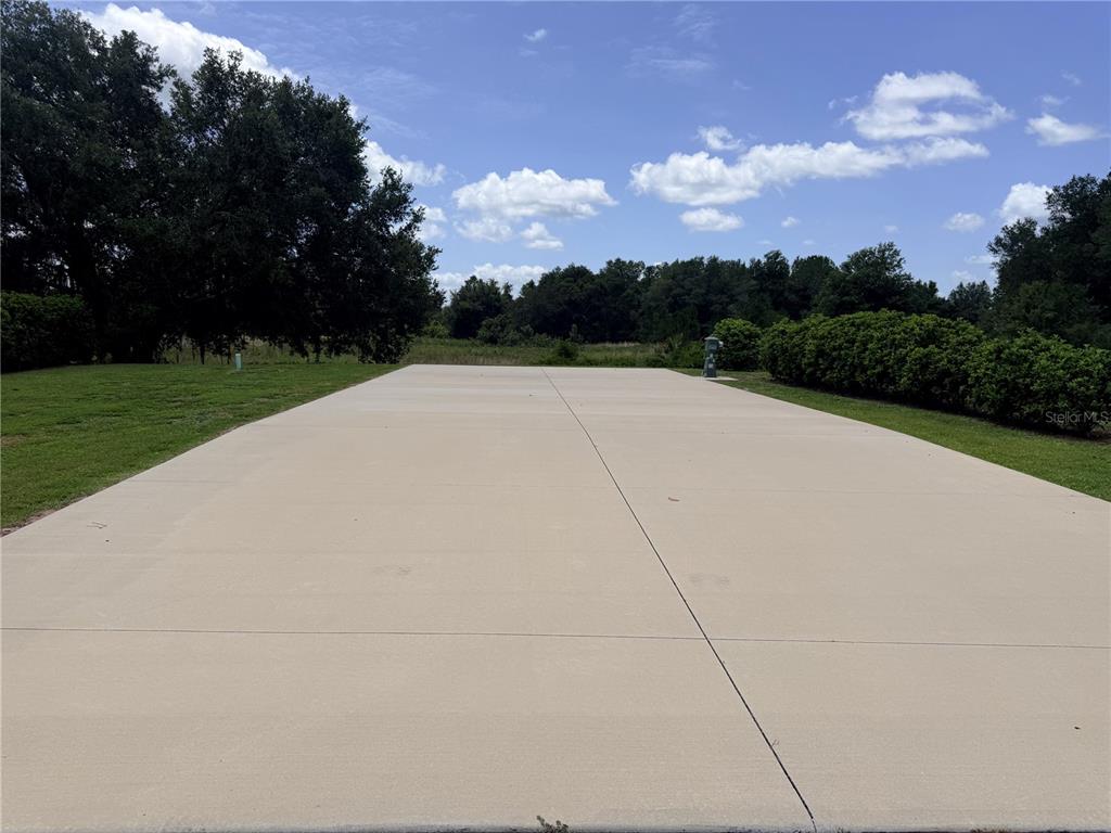 A large, rectangular concrete driveway sits in a grassy yard under a blue sky — 4879 SE 92ND BOULEVARD, WEBSTER, FL