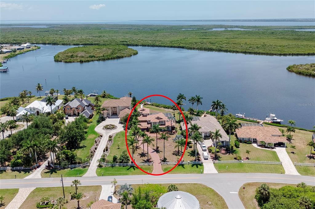An aerial view shows a waterfront house with a red roof and palm trees — 17501 OHARA DRIVE, PORT CHARLOTTE, FL