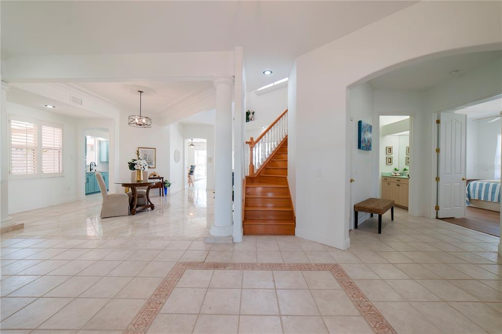 A foyer with tile flooring leads to a wooden staircase and an open dining area — 17501 OHARA DRIVE, PORT CHARLOTTE, FL