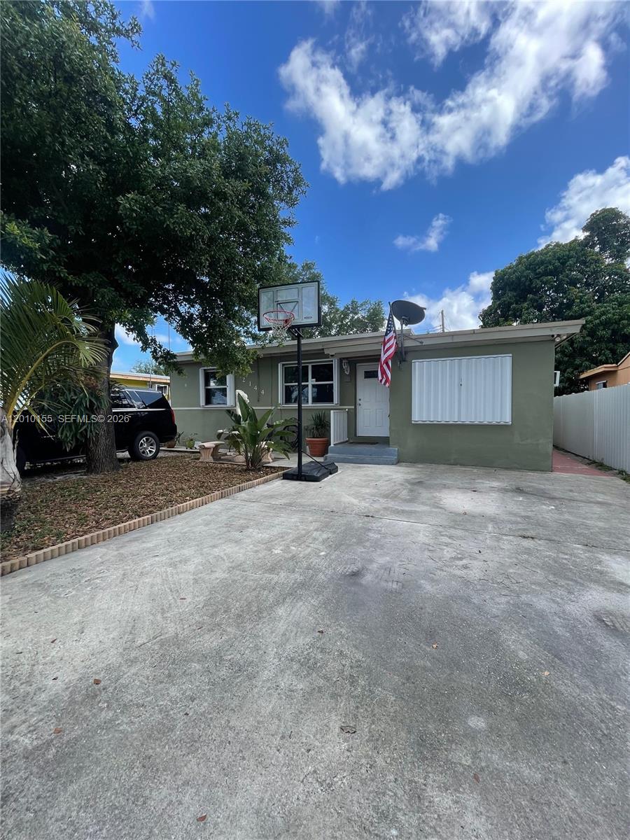 A single-story house with a concrete driveway, basketball hoop, and an American flag — 2144 NW 85th St, Miami FL 33147, MIAMI, FL