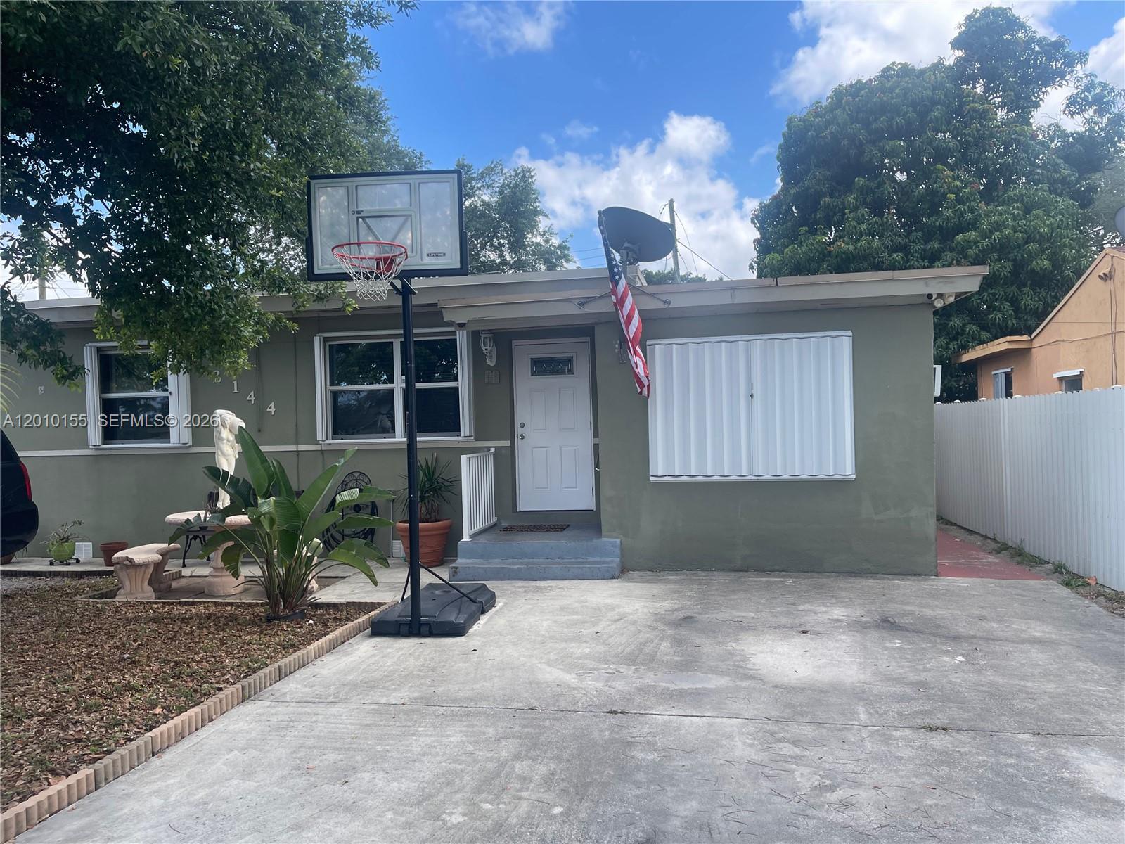 A single-story house with a concrete driveway, basketball hoop, and white accordion hurricane shutters — 2144 NW 85th St, Miami FL 33147, MIAMI, FL