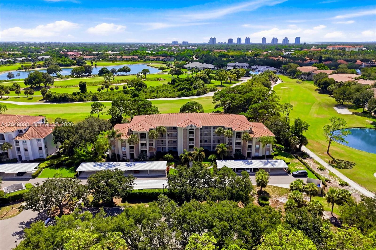 An aerial view shows a multi-story apartment building surrounded by a golf course and ponds — BONITA SPRINGS, FL