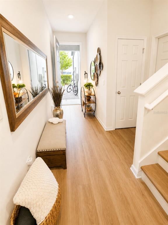 A bright entryway features light wood flooring, a bench, a mirror, and an open front door — 15613 WILLOW ARBOR CIRCLE, ORLANDO, FL