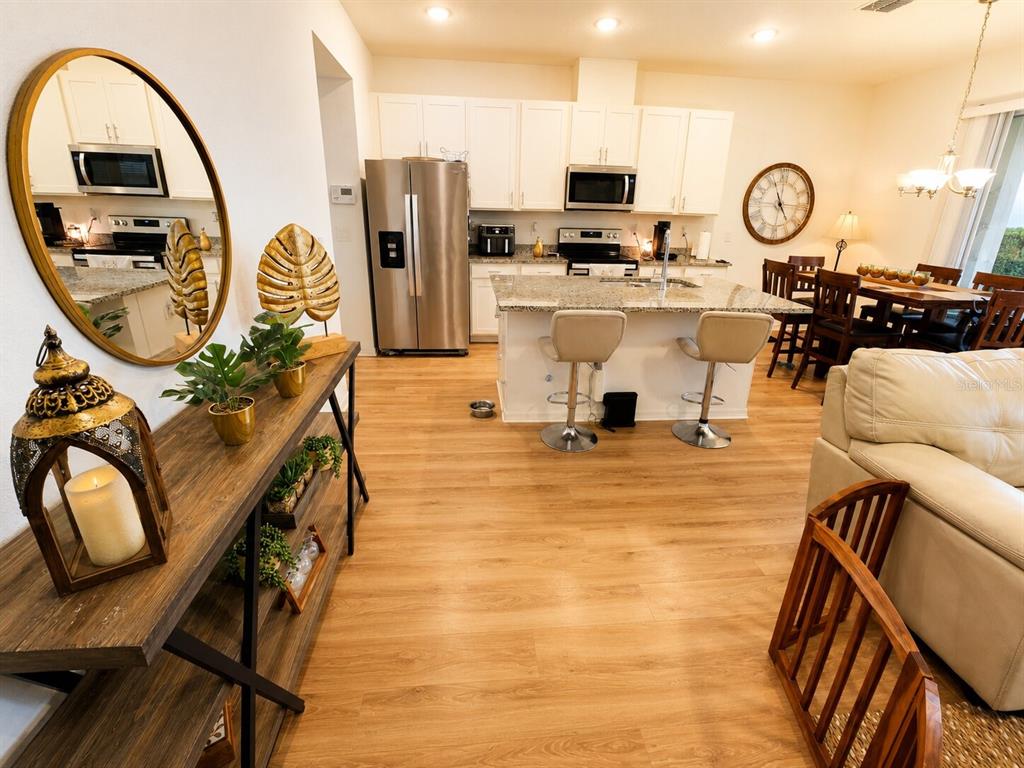 A kitchen with white cabinets, stainless steel appliances, and a granite island with two stools — 15613 WILLOW ARBOR CIRCLE, ORLANDO, FL