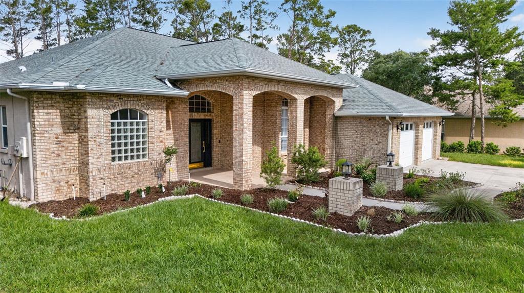 A single-story brick house features a covered arched entryway, a multi-car garage, and landscaping — 9363 TOOKE SHORE DRIVE, WEEKI WACHEE, FL