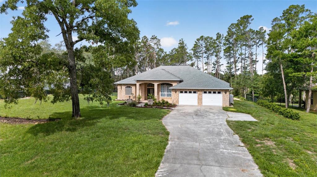 A single-story brick house with a two-car garage and a concrete driveway — 9363 TOOKE SHORE DRIVE, WEEKI WACHEE, FL