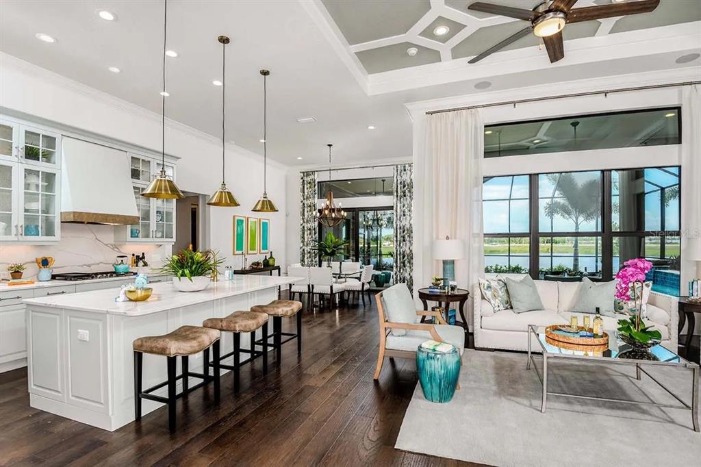 An open-concept kitchen and living area features a large island, hardwood floors, and floor-to-ceiling windows — 328 BOCELLI DRIVE, NORTH VENICE, FL