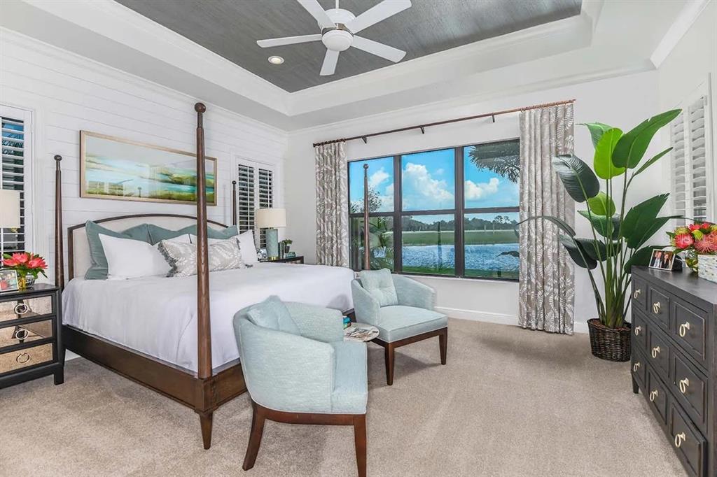 A bedroom features a four-poster bed, two light blue chairs, and a view of water — 328 BOCELLI DRIVE, NORTH VENICE, FL