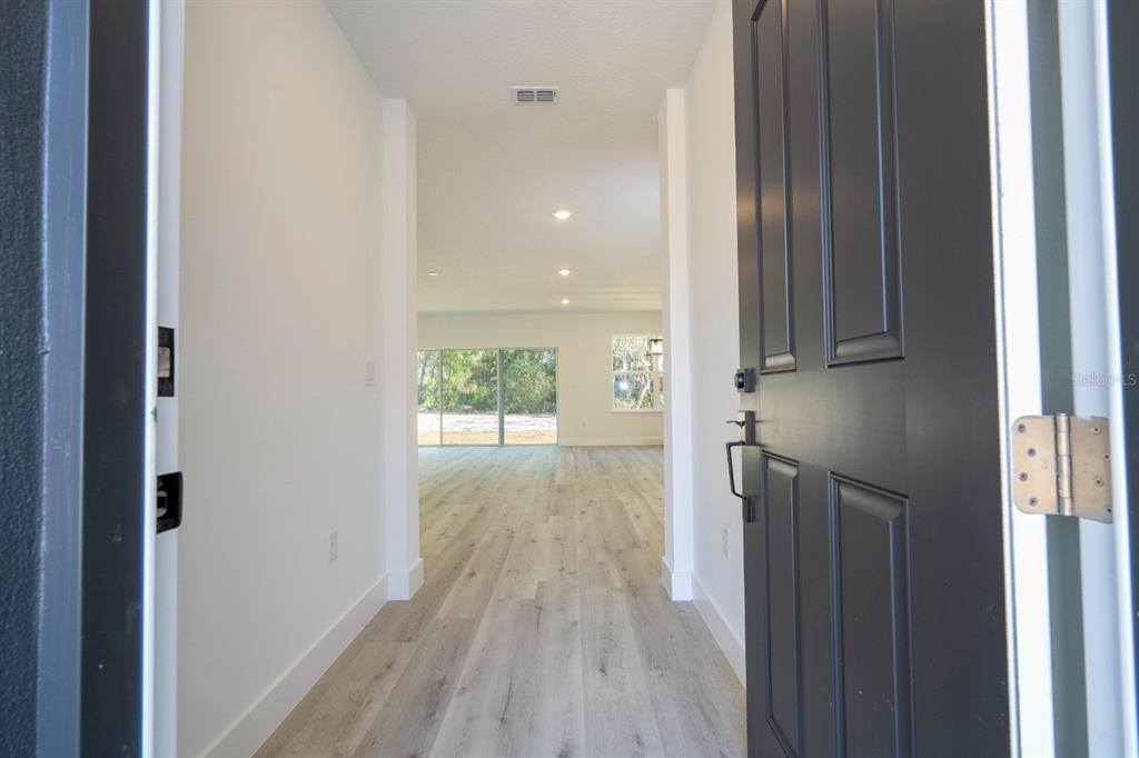 A view through an open dark front door into a bright entryway with light flooring — 1129 EDINBURGH STREET, NORTH PORT, FL