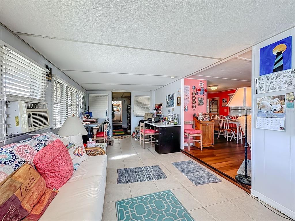 A sunroom with tile flooring leads into a dining area with wood floors and red walls — 411 TROPIC DRIVE W, PALMETTO, FL