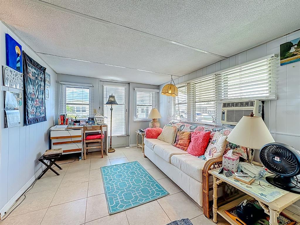 A living room features tile flooring, a white sofa, a desk, and window blinds — 411 TROPIC DRIVE W, PALMETTO, FL