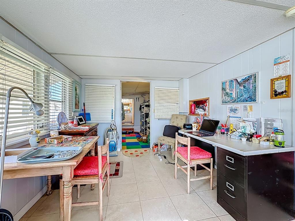 A sunroom features tile flooring, a wooden dining table, a desk, and a doorway leading inside — 411 TROPIC DRIVE W, PALMETTO, FL