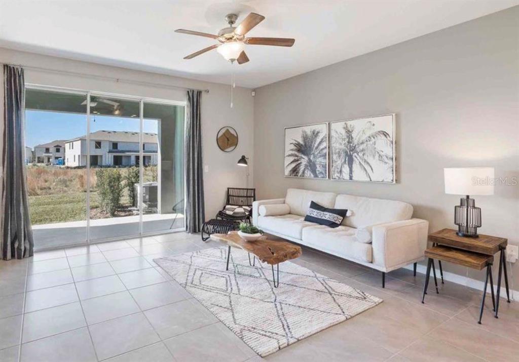 A living room features a white sofa, a wood coffee table, and a sliding glass door — 32202 TURTLE GRACE LOOP, WESLEY CHAPEL, FL