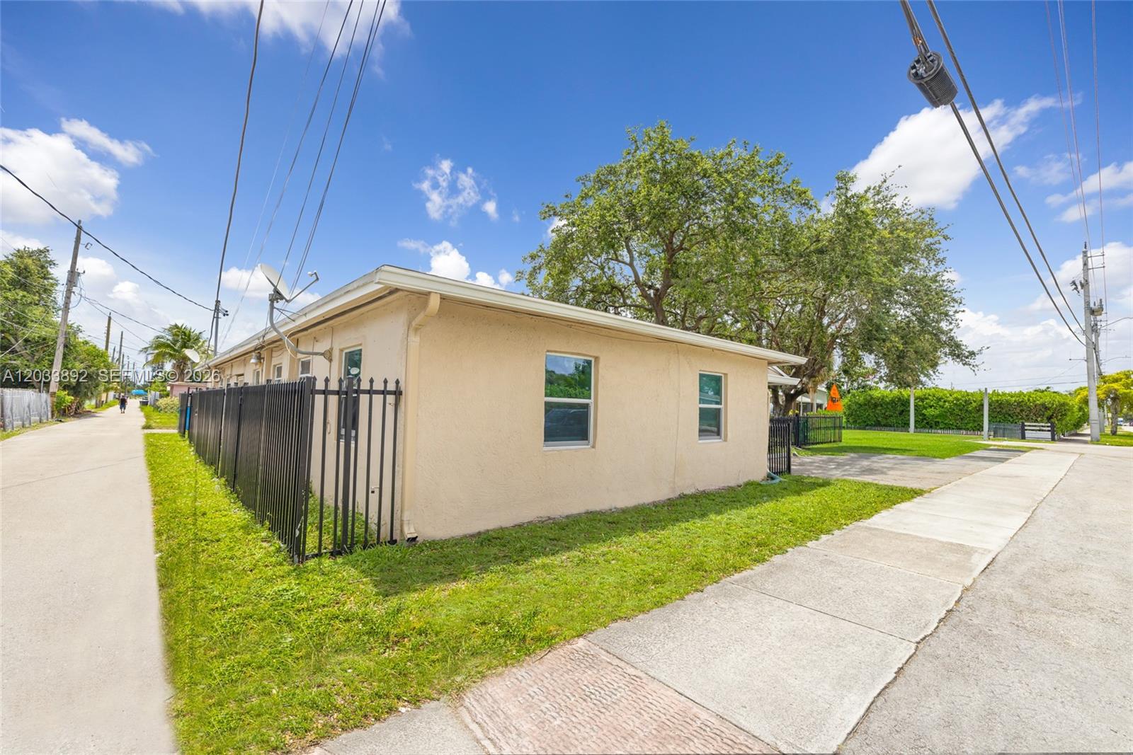 A beige, single-story house sits on a corner lot with a black metal fence — 2247 Simms St, Hollywood FL 33020, HOLLYWOOD, FL