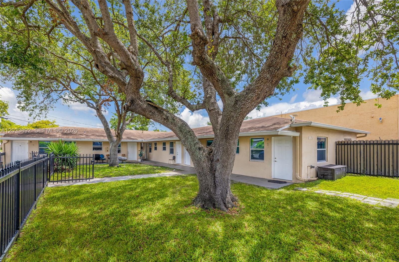 A single-story apartment building exterior features a grassy lawn and large shade trees — 2247 Simms St, Hollywood FL 33020, HOLLYWOOD, FL