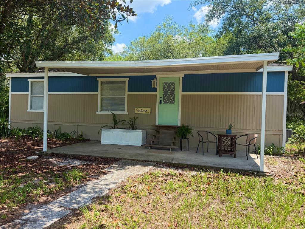 A single-story mobile home with a covered concrete porch, light green door, and blue trim — 31638 LAKE DRIVE, EUSTIS, FL