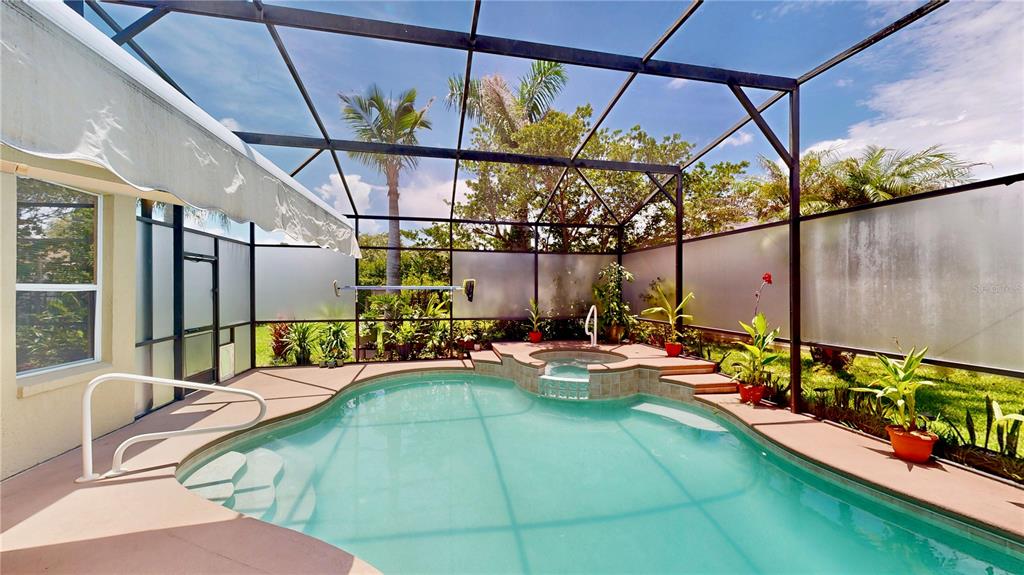 A screened-in swimming pool and hot tub area with a patio and tropical landscaping — 9101 WOODBRIDGE OAK TERRACE, ORLANDO, FL