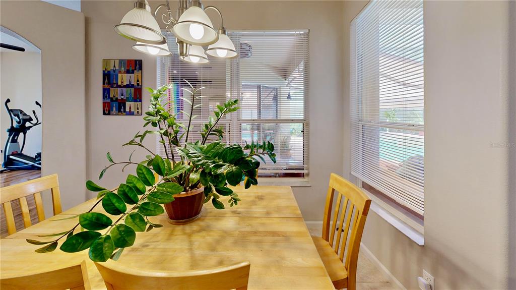 An open-concept living room and kitchen feature blue cabinets, light wood floors, and neutral furniture — 9101 WOODBRIDGE OAK TERRACE, ORLANDO, FL