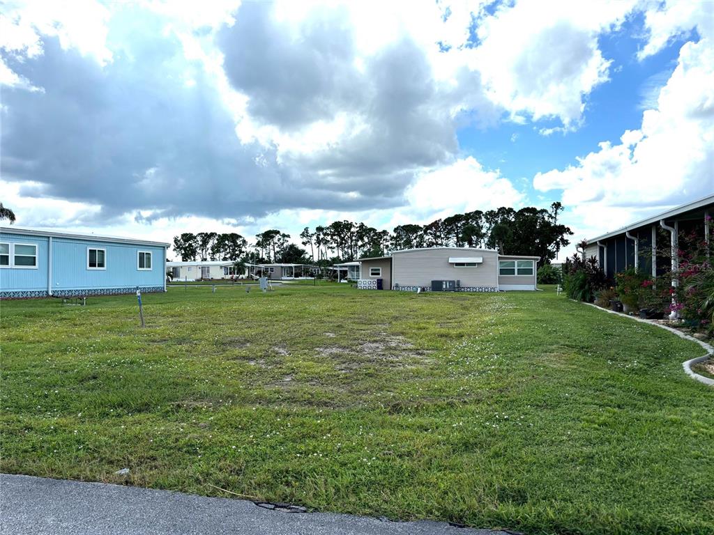 A grassy vacant lot sits between two mobile homes under a cloudy sky — 420 MADONNA, NORTH PORT, FL