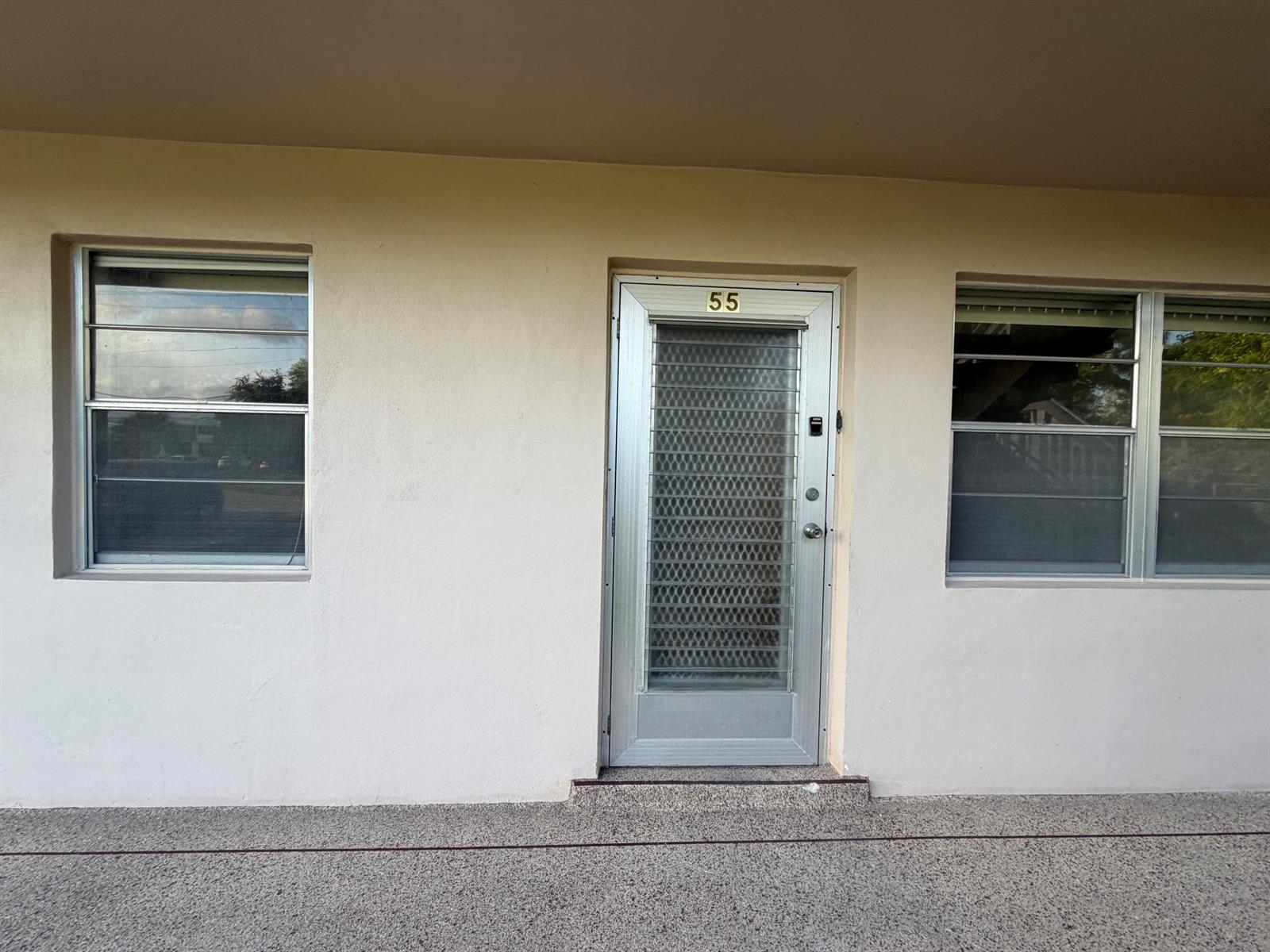 The exterior of a building features a central door numbered 55 flanked by two windows — 55 Hastings D, West Palm Beach FL 33417, WEST PALM BEACH, FL