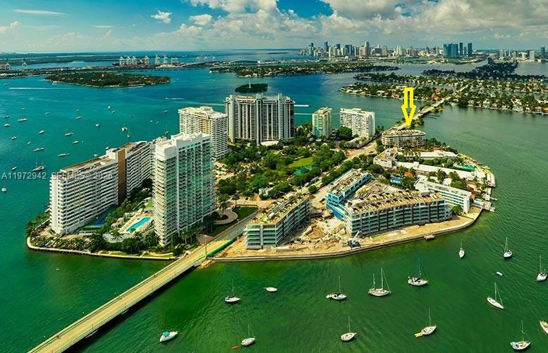 A palm tree stands before a waterfront view of a city skyline at sunset — 1 Century Ln # 310, Miami Beach FL 33139, MIAMI BEACH, FL