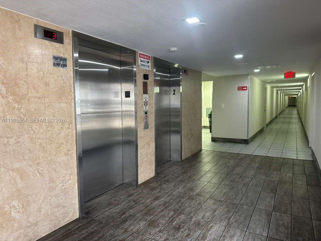 A hallway features two stainless steel elevators with tiled floors and beige wall panels — 8185 NW 7th St # 319, Miami FL 33126, MIAMI, FL