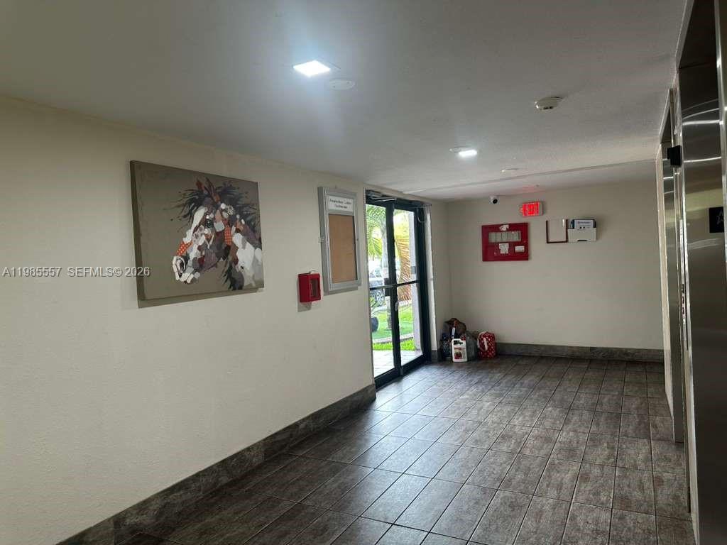 A tiled lobby area features a horse painting, a bulletin board, and a glass door — 8185 NW 7th St # 319, Miami FL 33126, MIAMI, FL