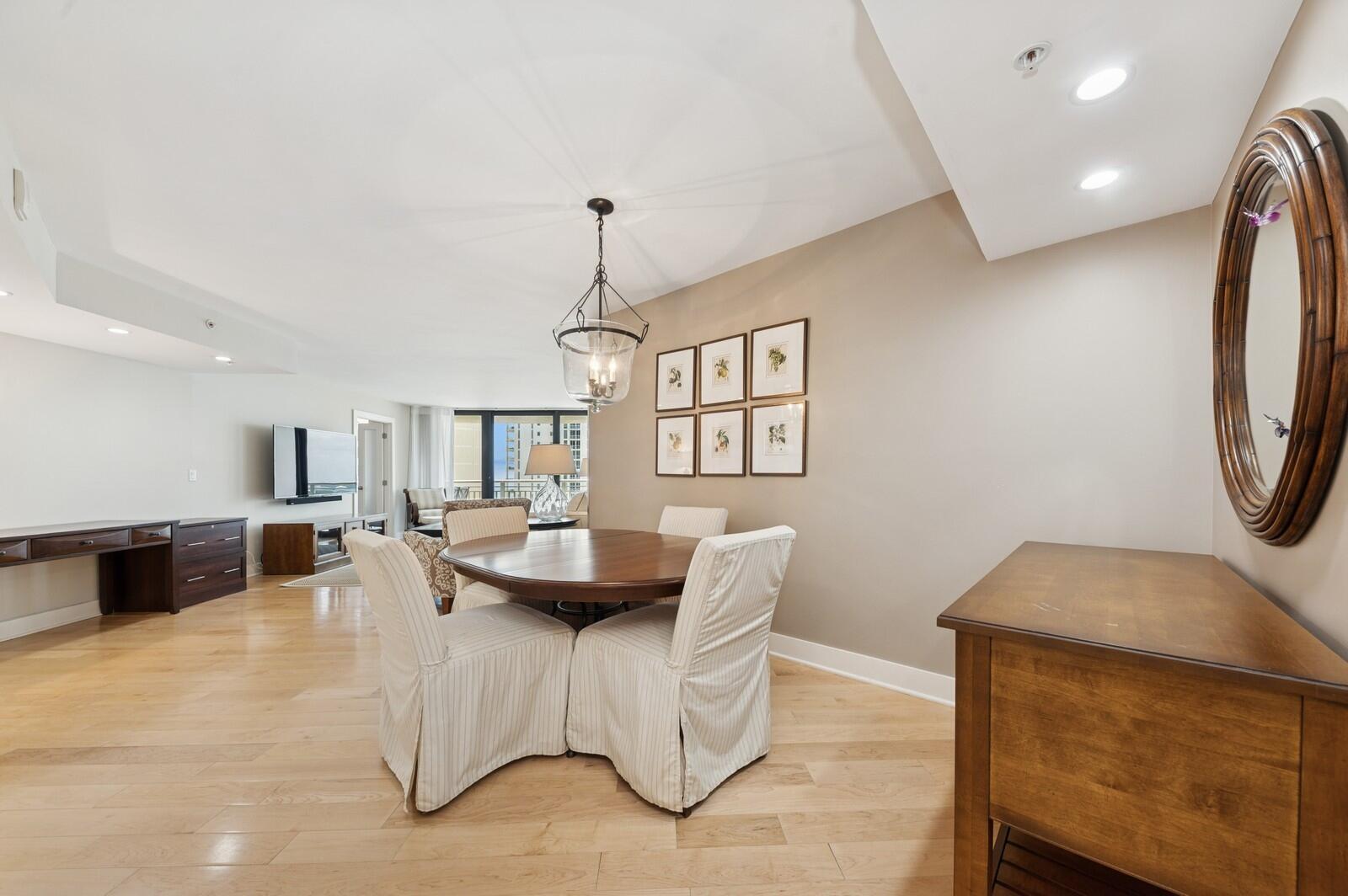 A dining area with a round wooden table, slipcovered chairs, and a wall-mounted mirror — 3000 N Ocean Drive # G, Singer Island FL 33404, SINGER ISLAND, FL