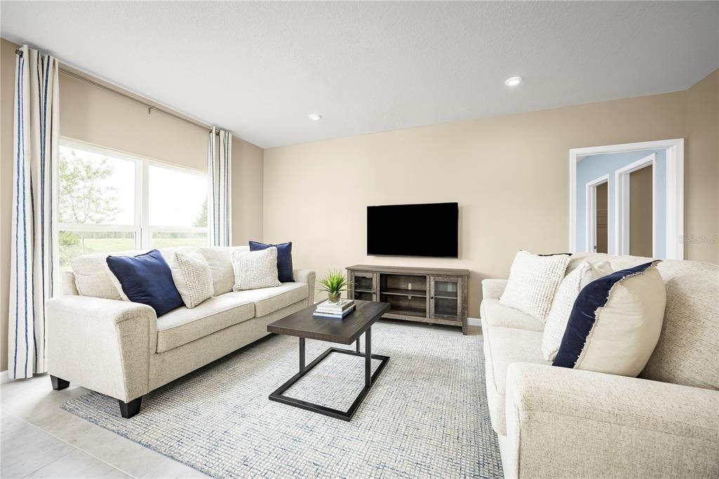 A living room features two beige sofas, a coffee table, a media console, and a rug — 512 171ST STREET E, BRADENTON, FL