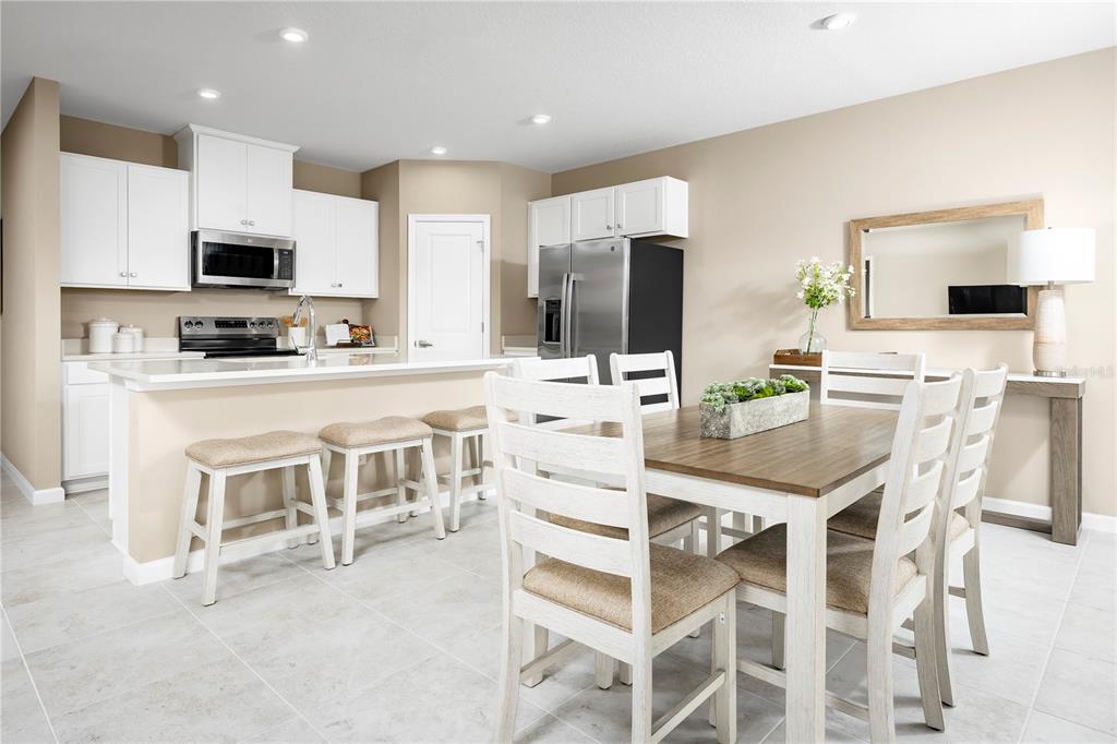 A kitchen with white cabinets and stainless steel appliances opens to a dining area — 512 171ST STREET E, BRADENTON, FL