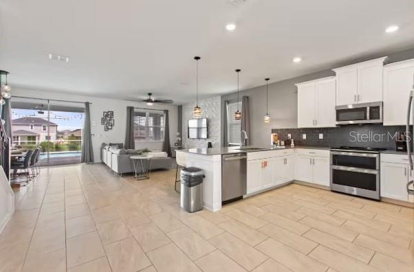 An open-concept kitchen with white cabinets and stainless steel appliances flows into a living area — 9298 SOMMERSET HILLS DRIVE, DAVENPORT, FL