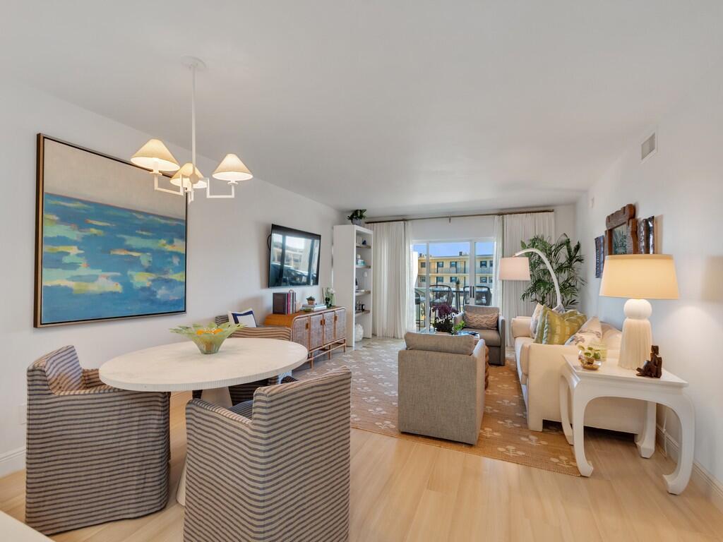 A bright living and dining room with striped chairs, a round table, and neutral furniture — 4049 Ocean Drive # 402, Vero Beach FL 32963, VERO BEACH, FL