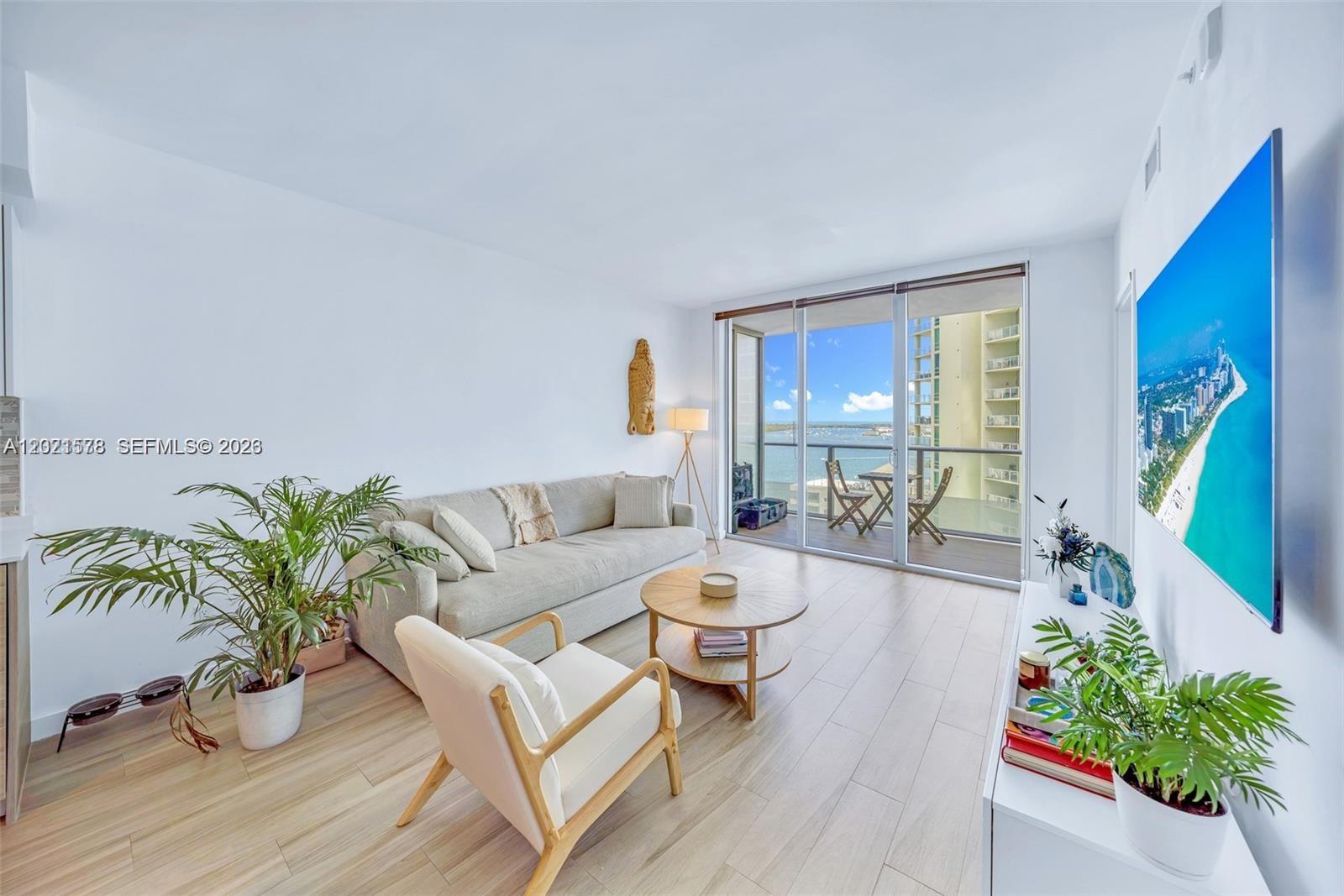 A living room features a sofa, armchair, coffee table, and a balcony overlooking the water — 1300 Brickell Bay Dr # 2104, Miami FL 33131, MIAMI, FL