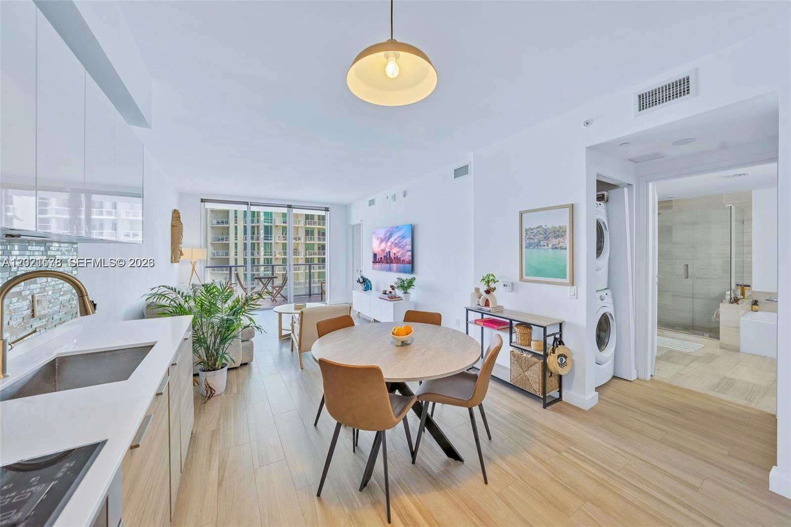 A bright, open-concept kitchen and dining area features light wood flooring and a balcony view — 1300 Brickell Bay Dr # 2104, Miami FL 33131, MIAMI, FL