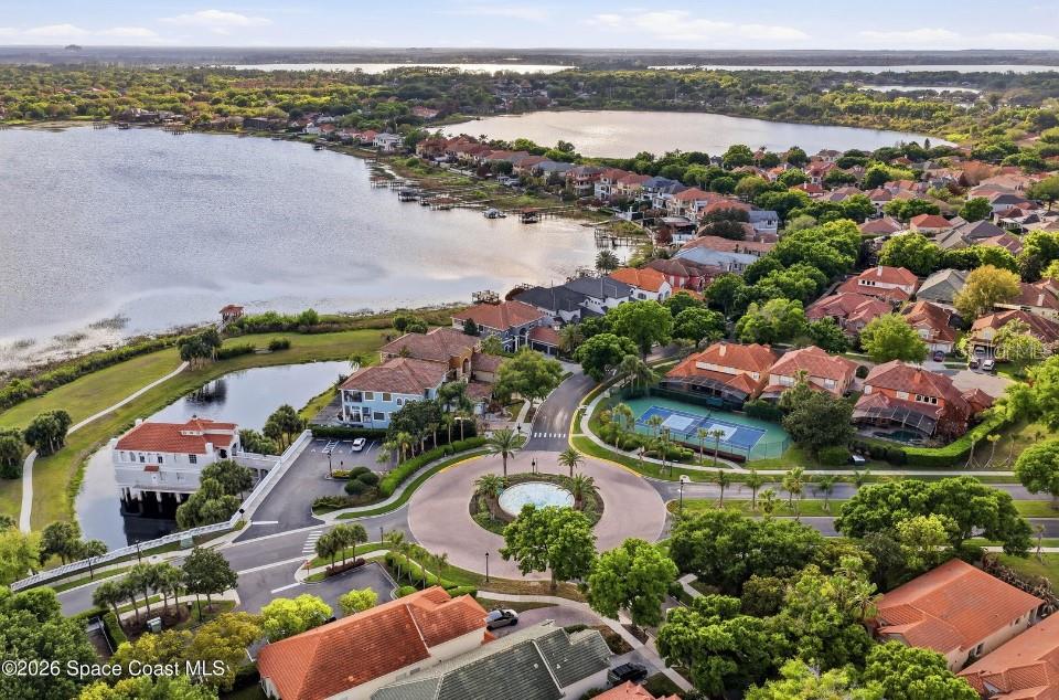 An aerial view shows a residential neighborhood with a circular roundabout, tennis court, and lake — 8760 THE ESPLANADE UNIT 51, ORLANDO, FL