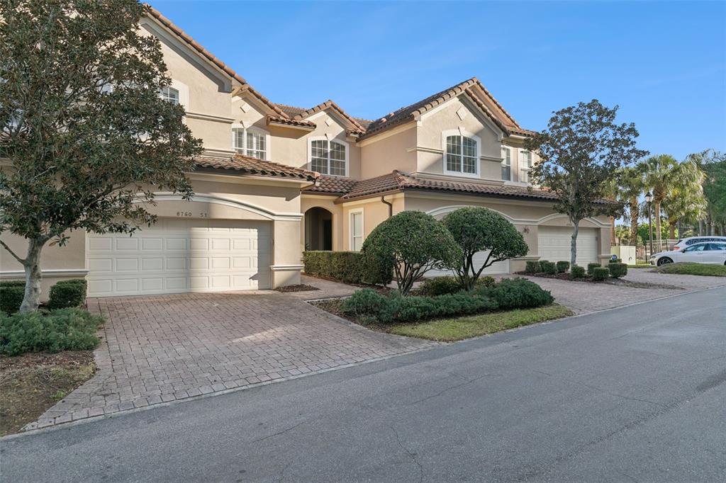 A two-story townhouse with a beige stucco exterior, tiled roof, and two attached garages — 8760 THE ESPLANADE UNIT 51, ORLANDO, FL
