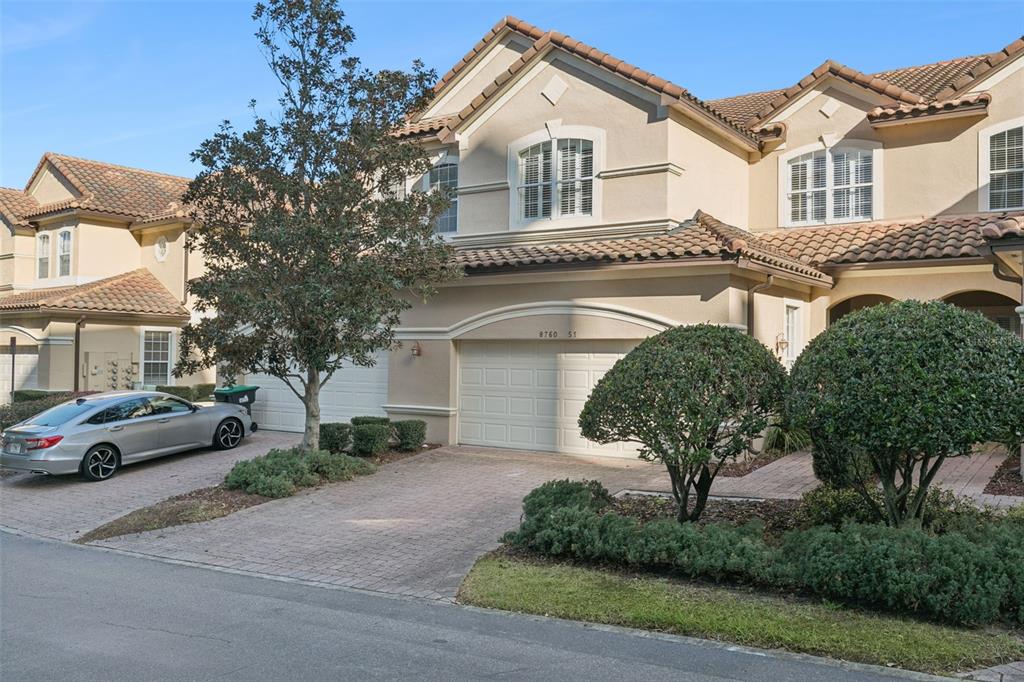 A two-story stucco townhouse with a tile roof, a two-car garage, and a paved driveway — 8760 THE ESPLANADE UNIT 51, ORLANDO, FL