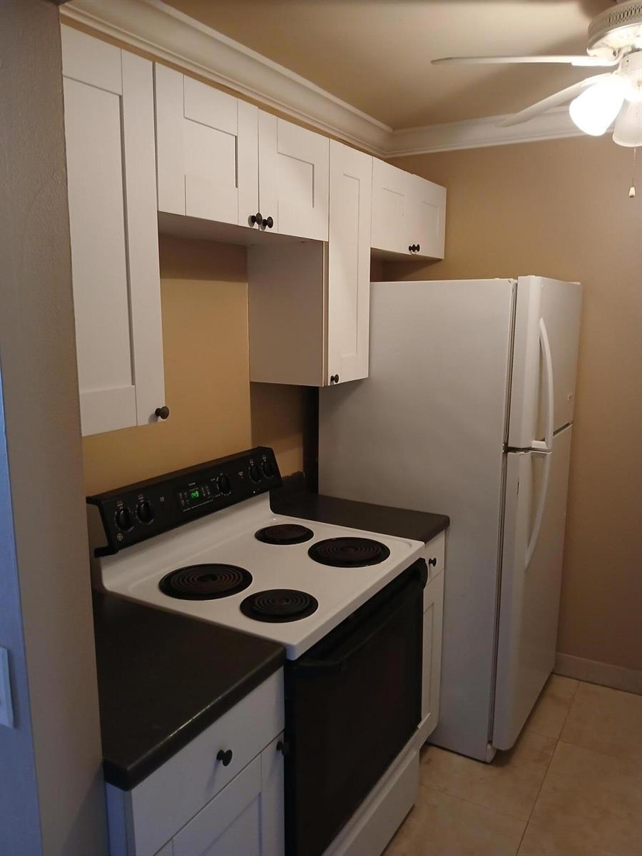 A small kitchen featuring white cabinets, a white electric stove, and a white refrigerator — 250 Durham # F, Deerfield Beach FL 33442, DEERFIELD BEACH, FL