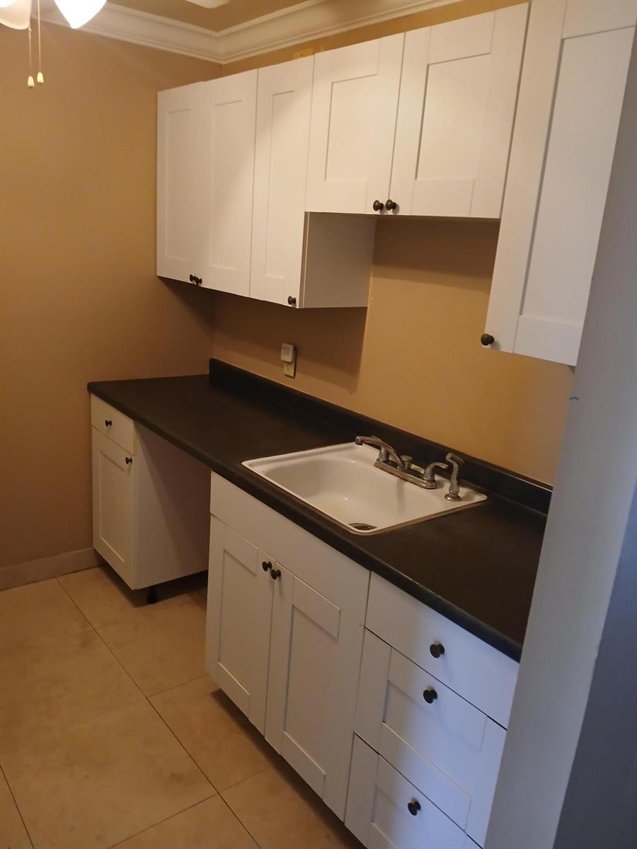 A kitchen area features white shaker cabinets, a dark countertop, and a white drop-in sink — 250 Durham # F, Deerfield Beach FL 33442, DEERFIELD BEACH, FL