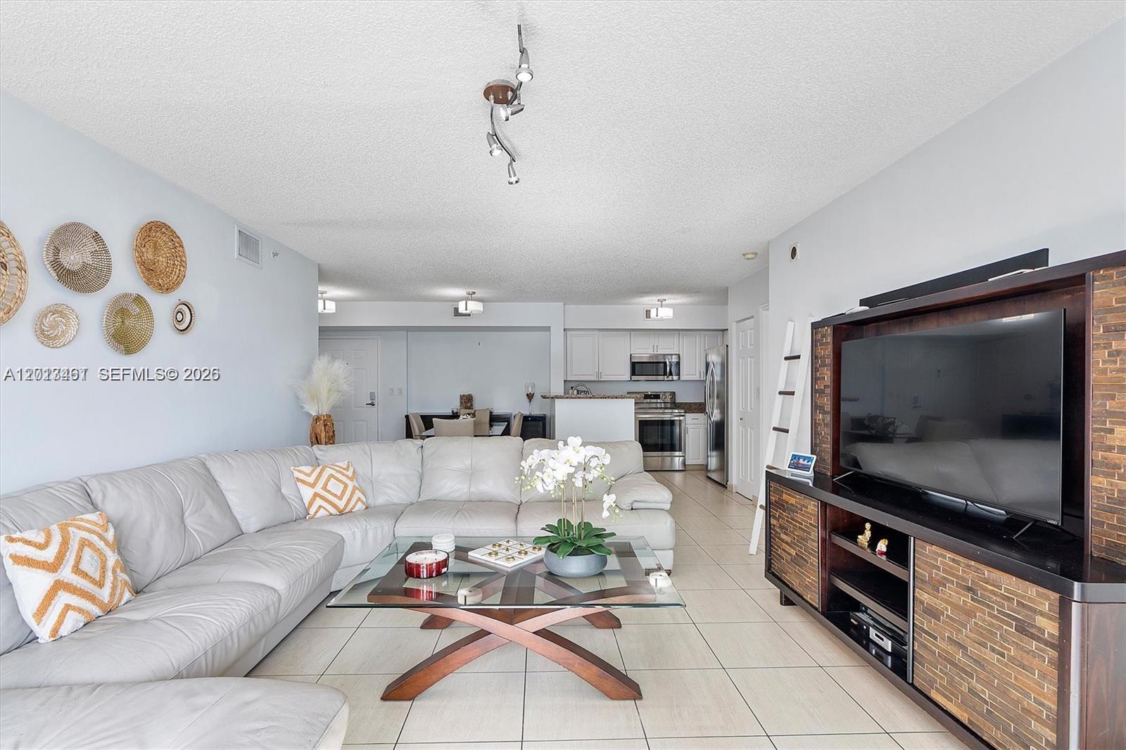 A living room features a white sectional sofa, a glass coffee table, and a media console — 1155 Brickell Bay Dr # 603, Miami FL 33131, MIAMI, FL