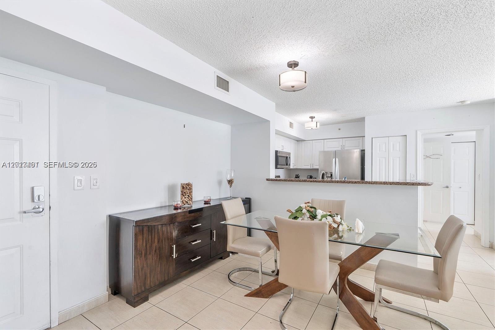 A dining area features a glass table, beige chairs, and a dark wood sideboard — 1155 Brickell Bay Dr # 603, Miami FL 33131, MIAMI, FL