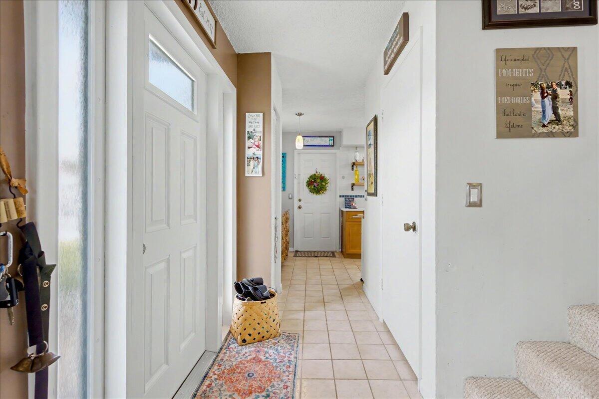 A tiled entryway leads to a hallway with a white door and a wicker basket — 6198 Riverwalk Lane # 1, Jupiter FL 33458, JUPITER, FL