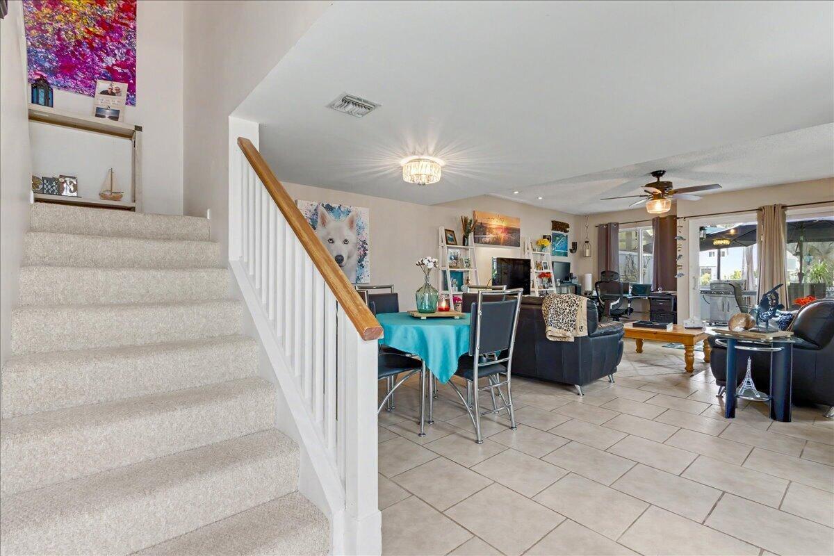 A carpeted staircase leads to an open-concept living and dining area with tile flooring — 6198 Riverwalk Lane # 1, Jupiter FL 33458, JUPITER, FL