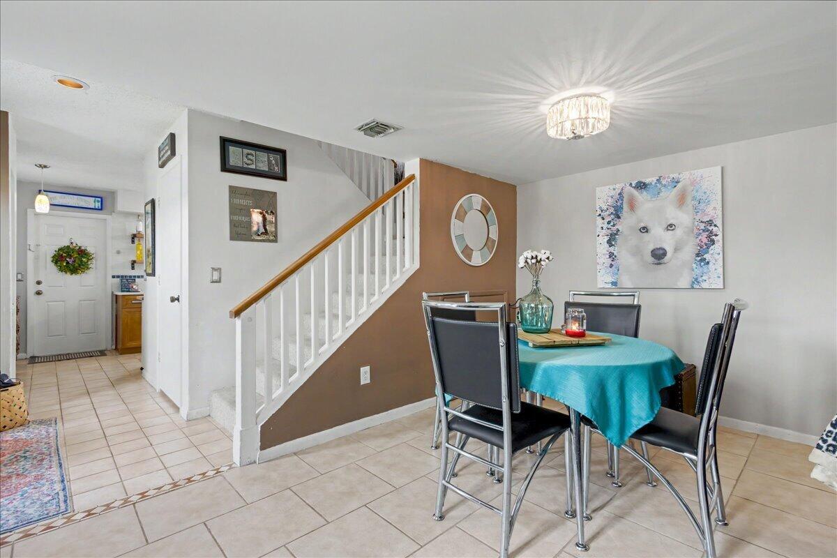 A dining area features a round table, modern chairs, and a staircase with white railings — 6198 Riverwalk Lane # 1, Jupiter FL 33458, JUPITER, FL