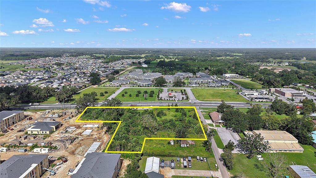 An aerial view shows a vacant, tree-covered lot outlined in yellow near a busy road — 11535 N US 301, OXFORD, FL