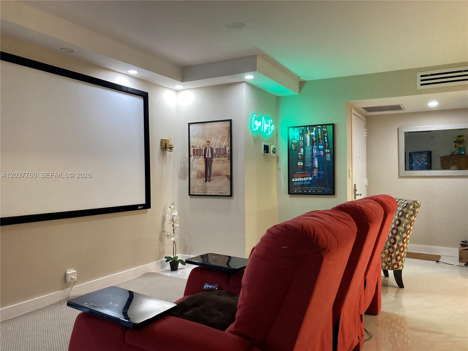 A home theater room features a large projection screen, red reclining chairs, and framed posters — 6767 Collins Ave # 1701, Miami Beach FL 33141, MIAMI BEACH, FL