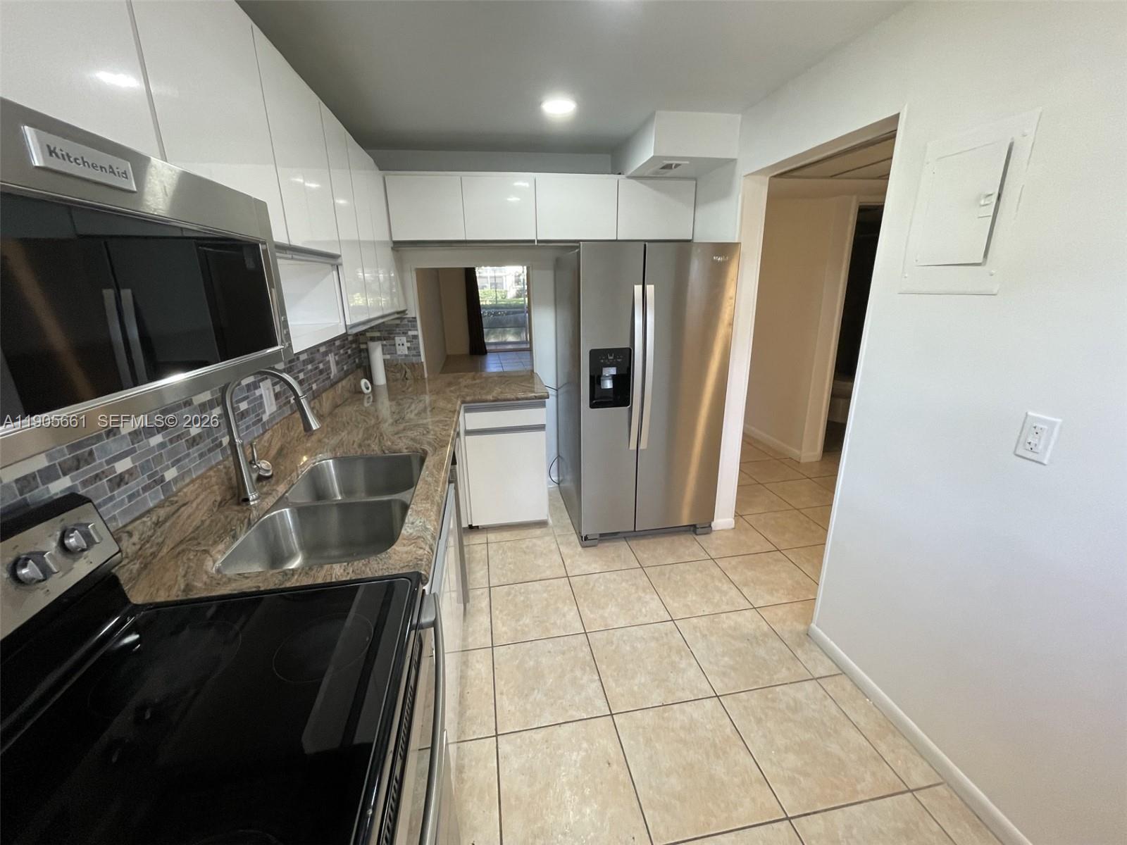 A kitchen features stainless steel appliances, white cabinets, granite countertops, and light-colored floor tiles — 4500 N Federal Hwy # 102A, Lighthouse Point FL 33064, LIGHTHOUSE POINT, FL