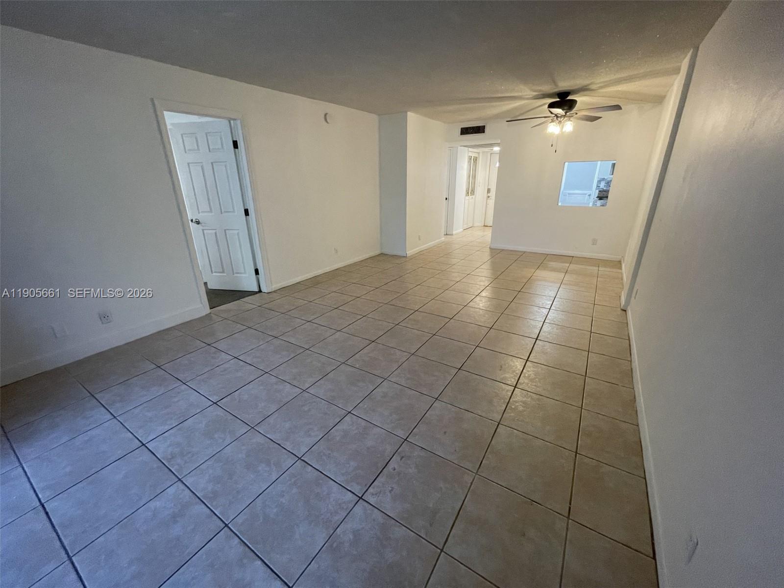 An empty room features white walls, tan tile flooring, a ceiling fan, and a doorway — 4500 N Federal Hwy # 102A, Lighthouse Point FL 33064, LIGHTHOUSE POINT, FL